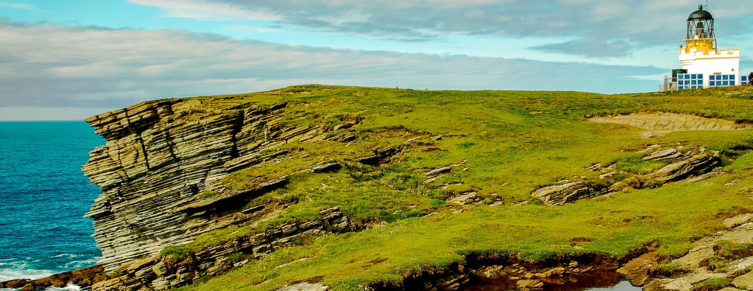 Leuchtturm auf grüner Felsenküste